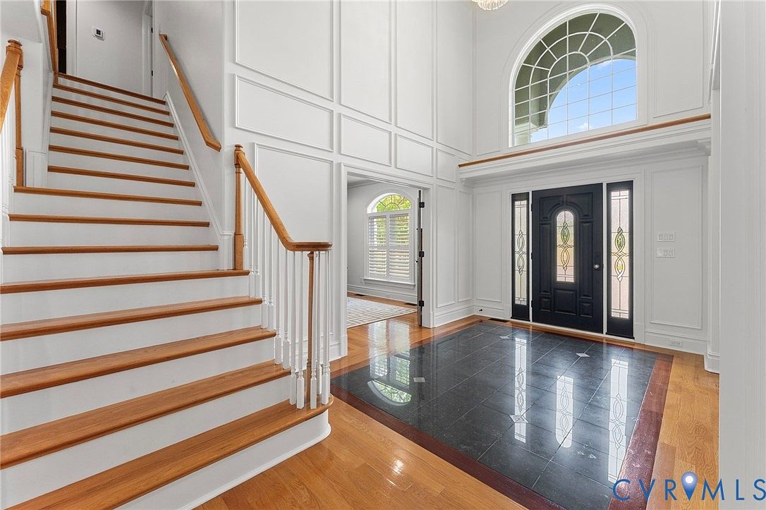 Oak staircase ascending from the foyer with white turned spindles and a runner of hardwood flooring across the second-floor balcony