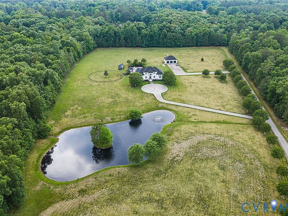 Aerial view showing the full 20.3-acre parcel: brick estate, circular drive, pool, detached workshop, and a perimeter of mature Virginia woodland